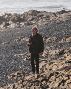 Homme regardant au loin sur une plage de galets